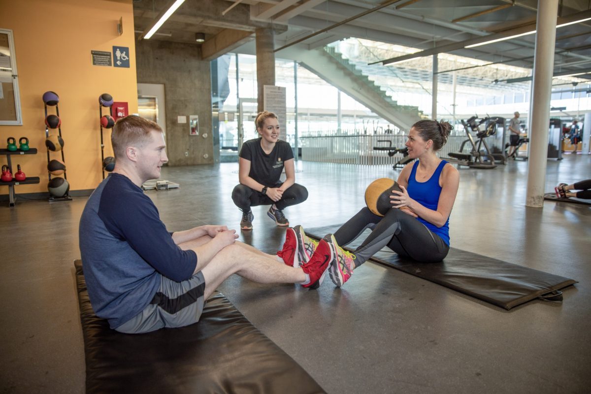 A trio of people sitting and chatting in the Active Living Centre gym.