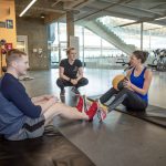 A trio of people sitting and chatting in the Active Living Centre gym.