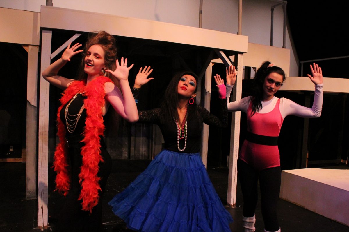 Three female performers with arms raised from the play Macbeth