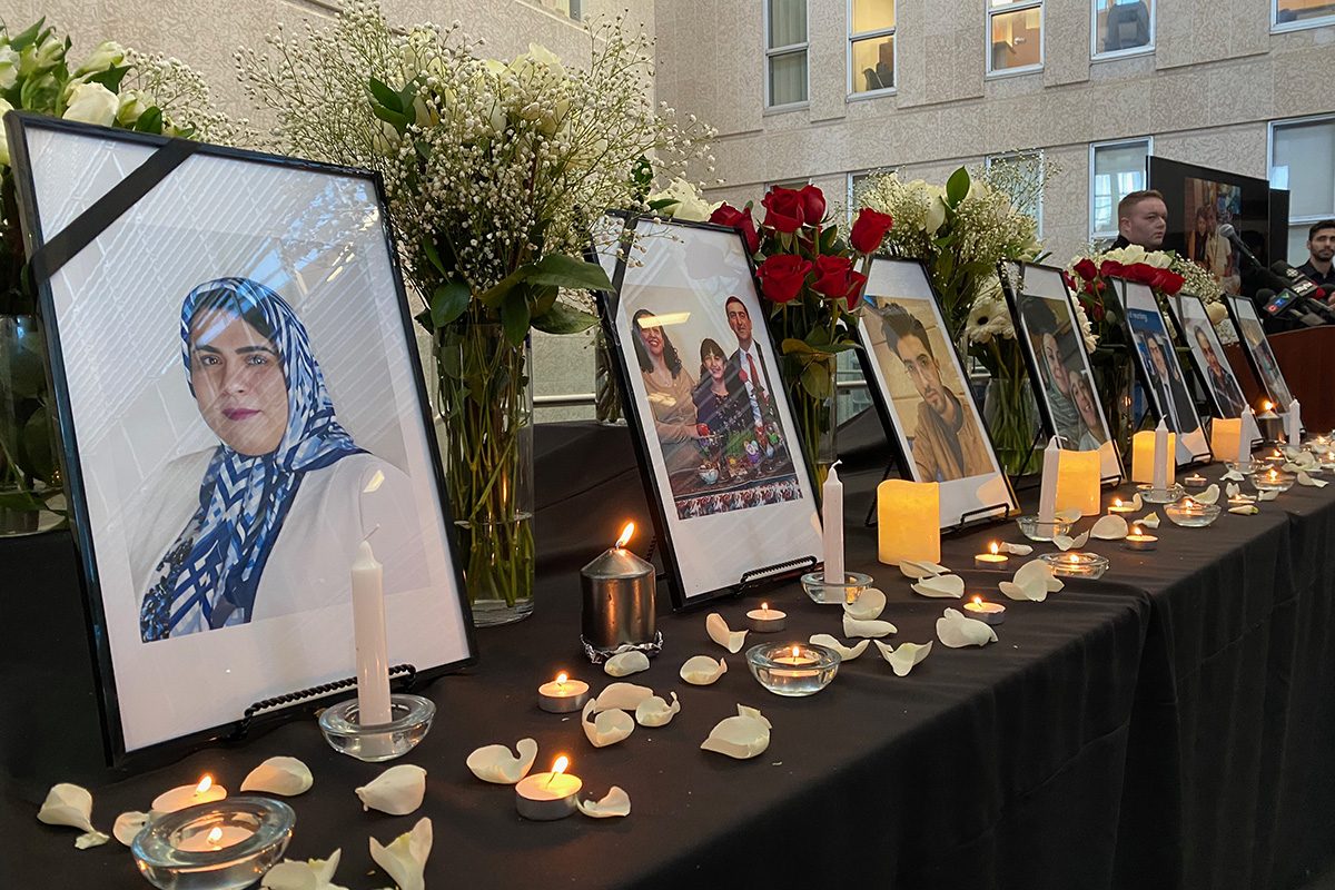 Photos of the plane crash victims are displayed on a table, with candles lit in front of the photos, at a vigil on Jan. 10, 2020.