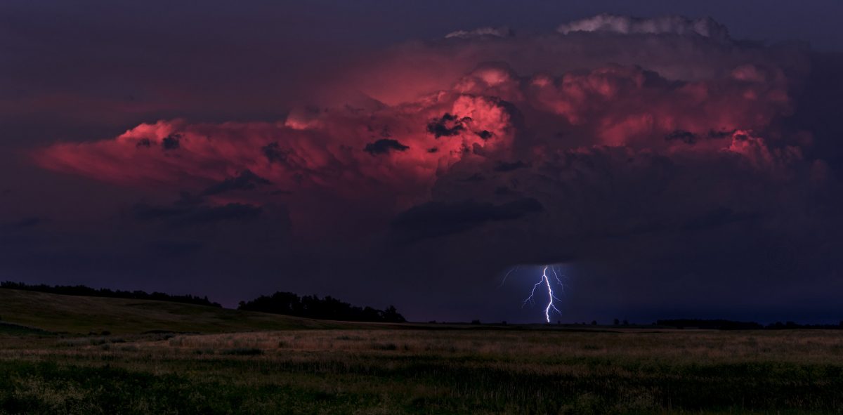 A pink cloud at sunset throws a lightning bolt to the Prairie below
