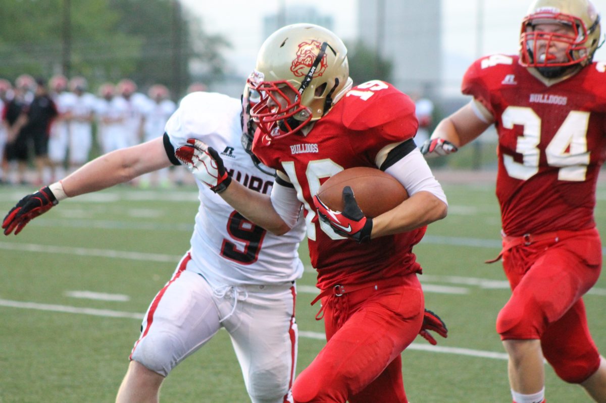 A football player running with the football trying to break a tackle