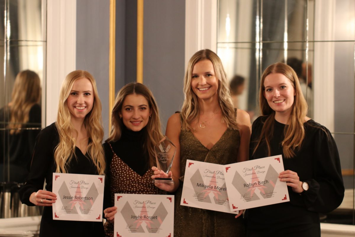 Four young women in formal wear pose for photo smiling, holding certificates and a glass award.