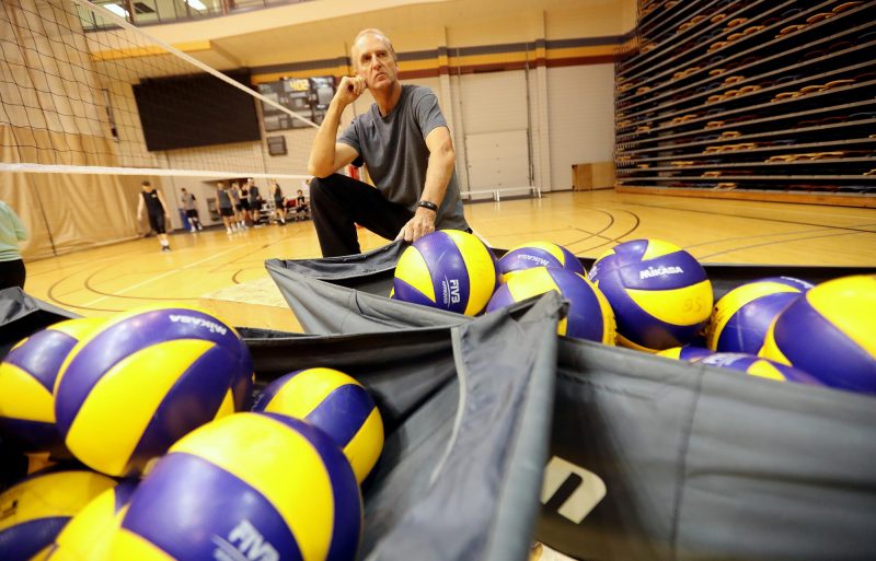 Garth Pischke sits on volleyball court with volleyballs
