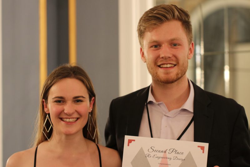 A young woman, left, and a young man, right smiling for photo holding certificate. 