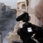 Syrian woman filming a street filled with war activities