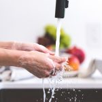 Person washing hands, food in background