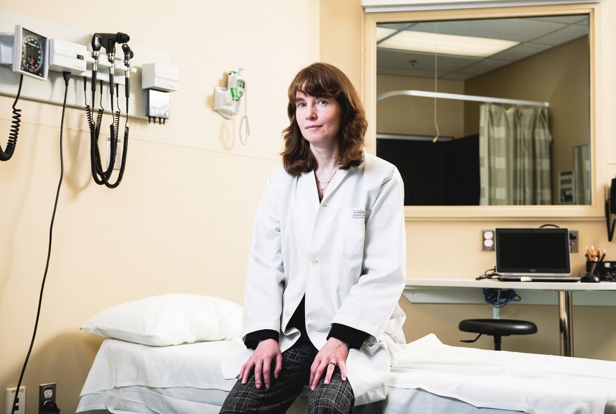 A young female doctor sits in a hospital room.