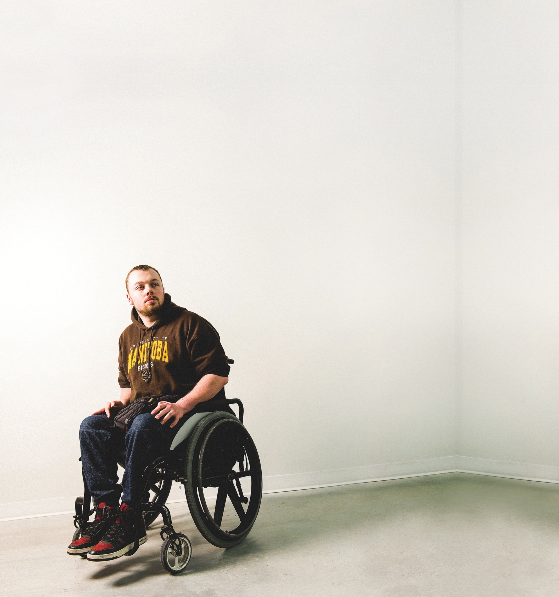 Andrew Fenwick sits in a wheelchair in an empty room.