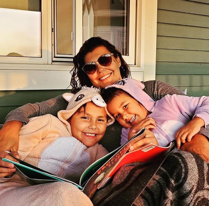 Dr. Marcia Anderson and her daughters reading a book in the evening sun.