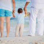 A child with his parents at the beach. // Image from Pixabay