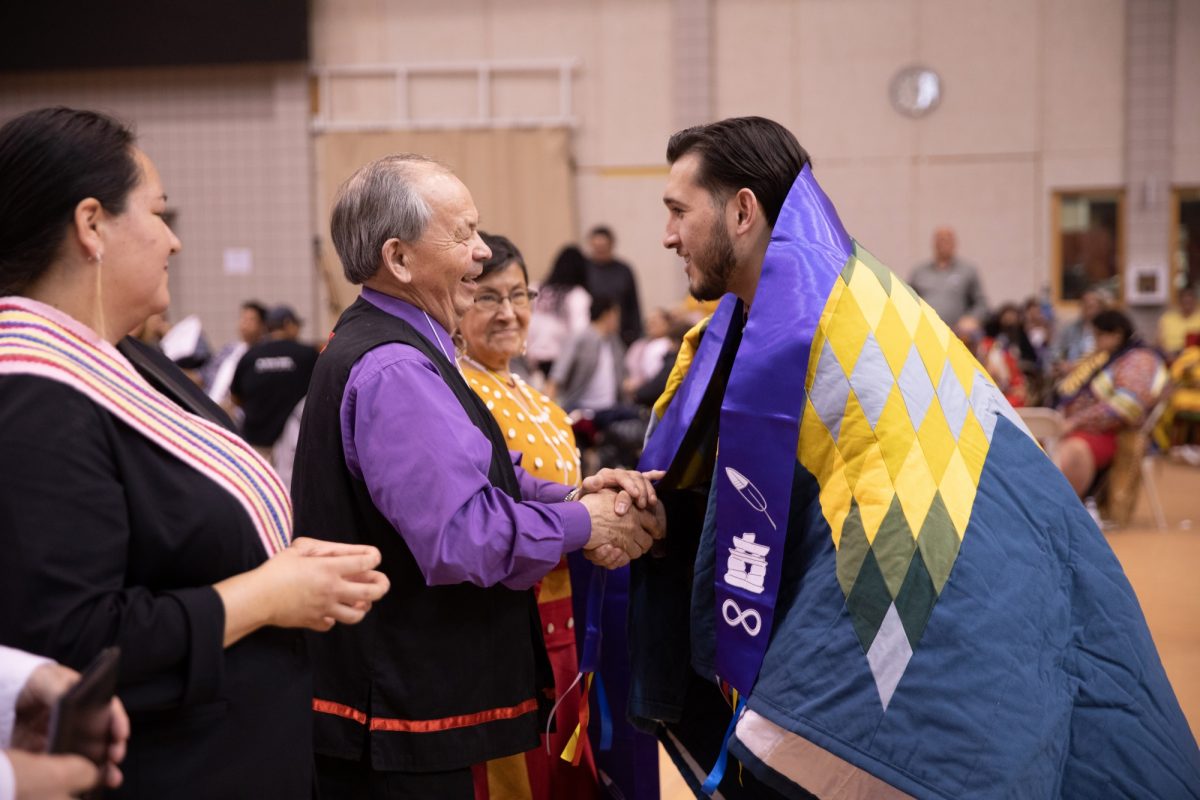 An Indigenous student shaking hands with an Elder at the 2019 Traditional Graduation Pow Wow