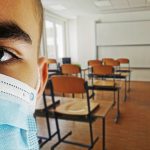 Close up of person wearing a mask in an empty classroom