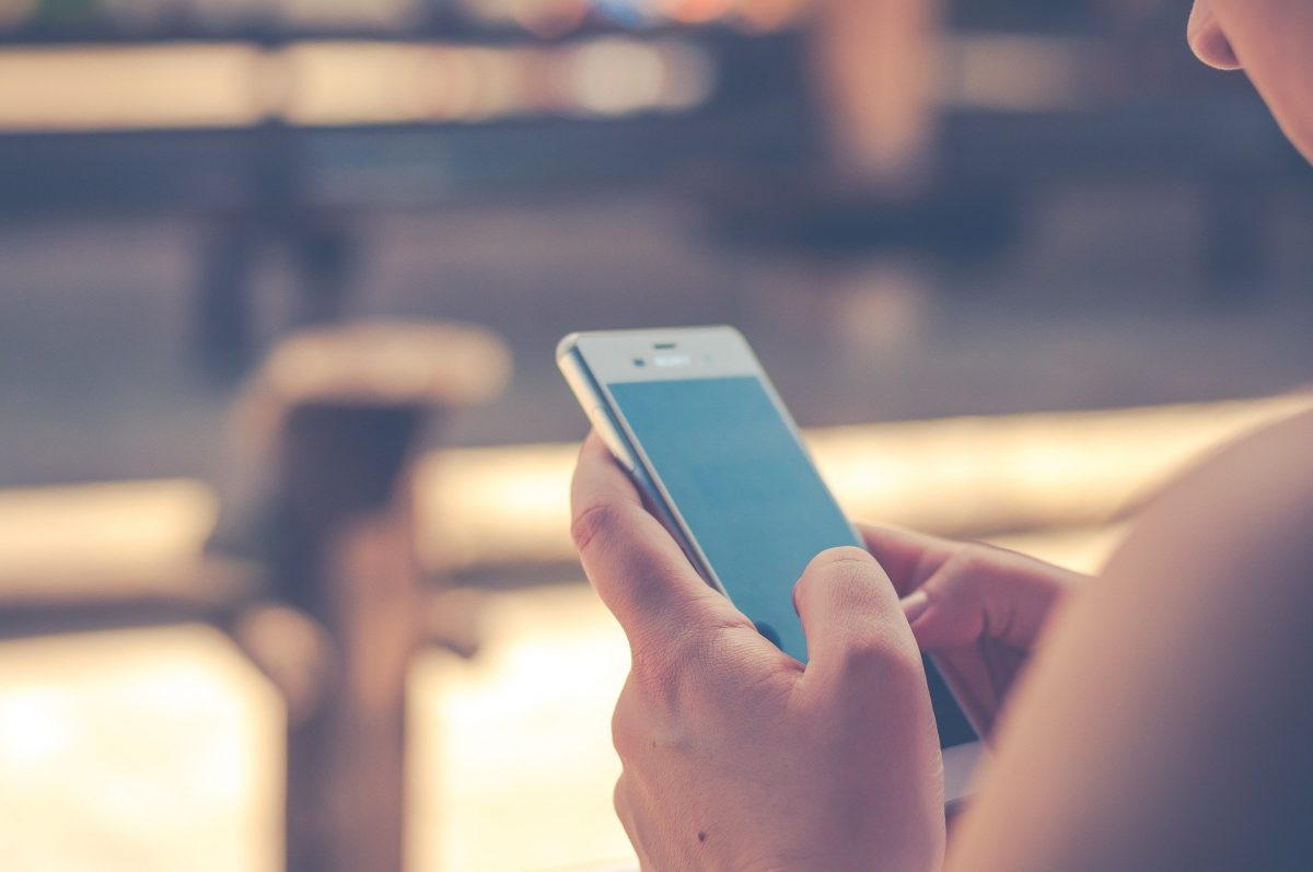 Female holds smartphone in her hand, inputting text