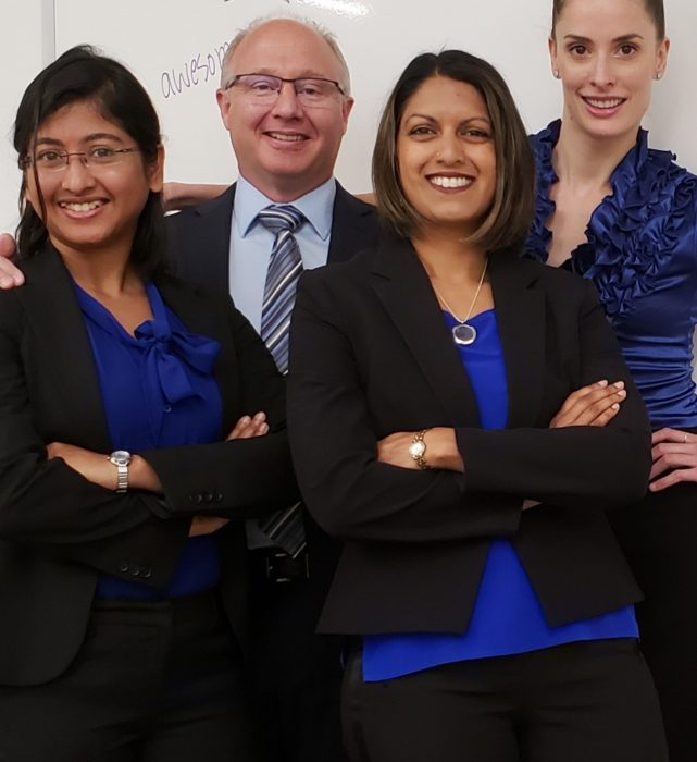 Group of people dressed in business attire smiling with their arms crossed.
