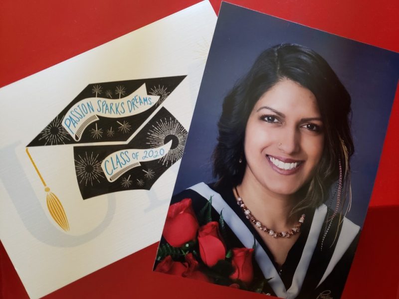 A graduation picture of Larissa sits on a red background with a congratulations card beside it.