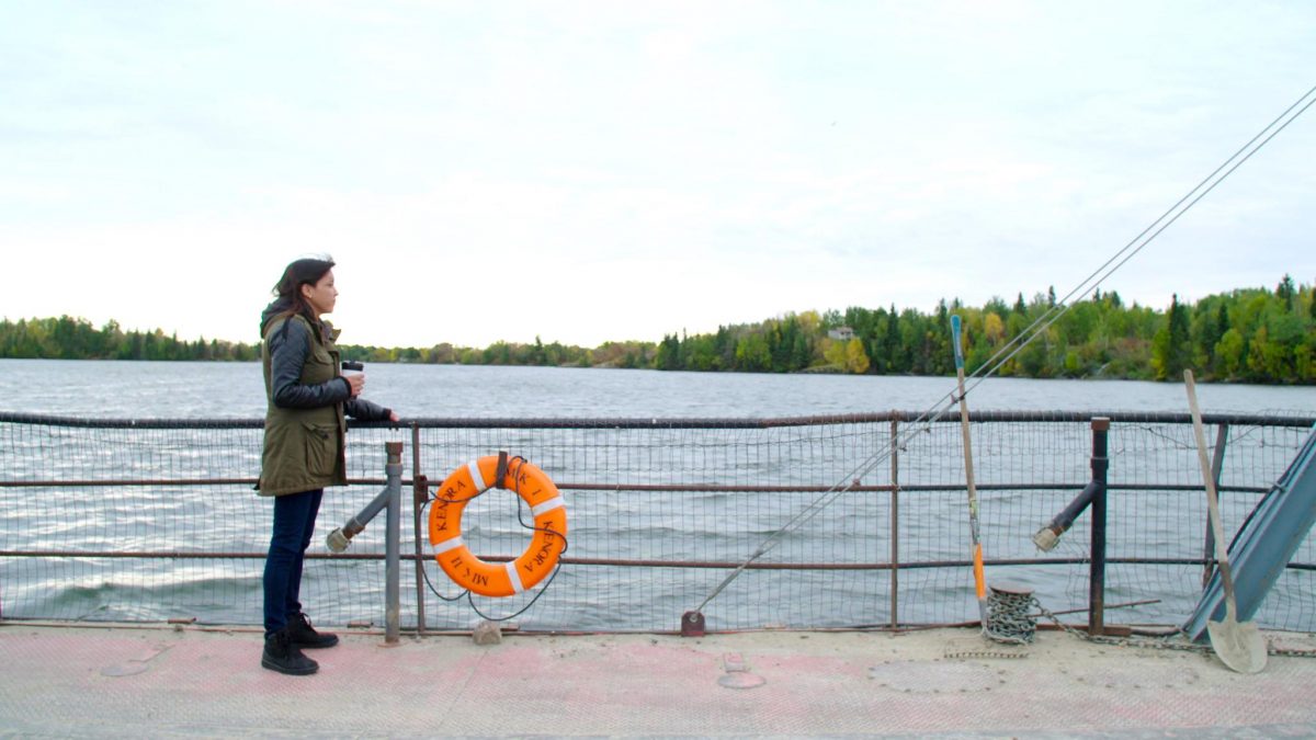 Angelina McLeod stands on a ferry on the water.