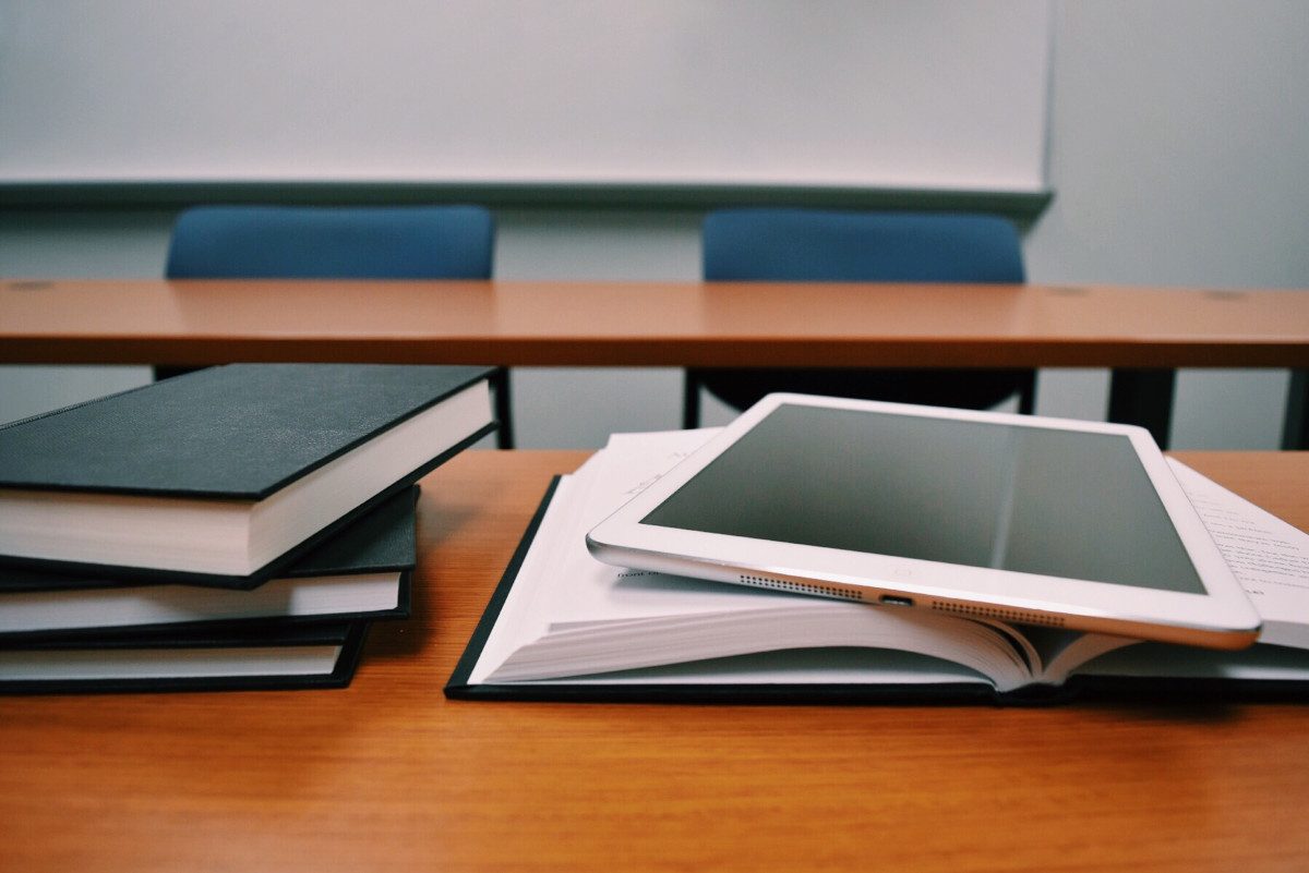 Books and computer tablet on classroom table
