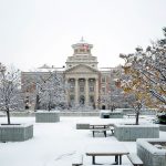 Snow covers the ground and trees around the Administration Building on Fort Garry campus.