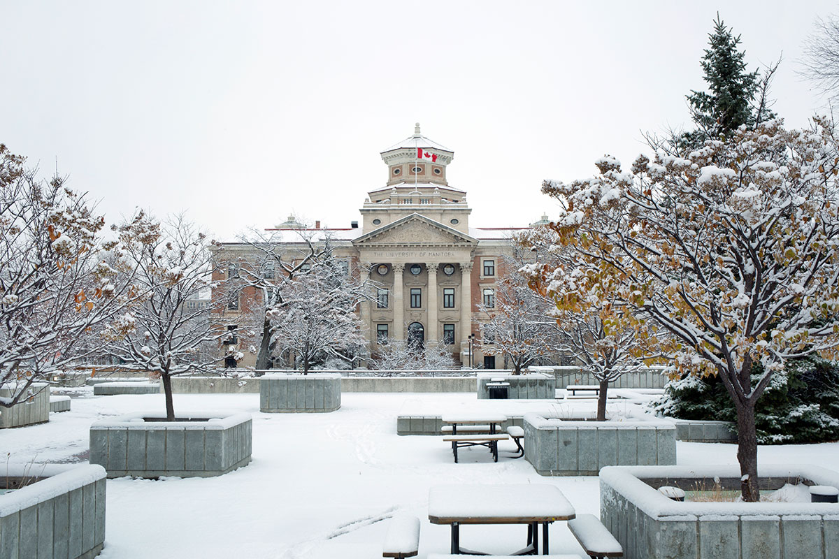 Snow covers the ground and trees around the Administration Building on Fort Garry campus.