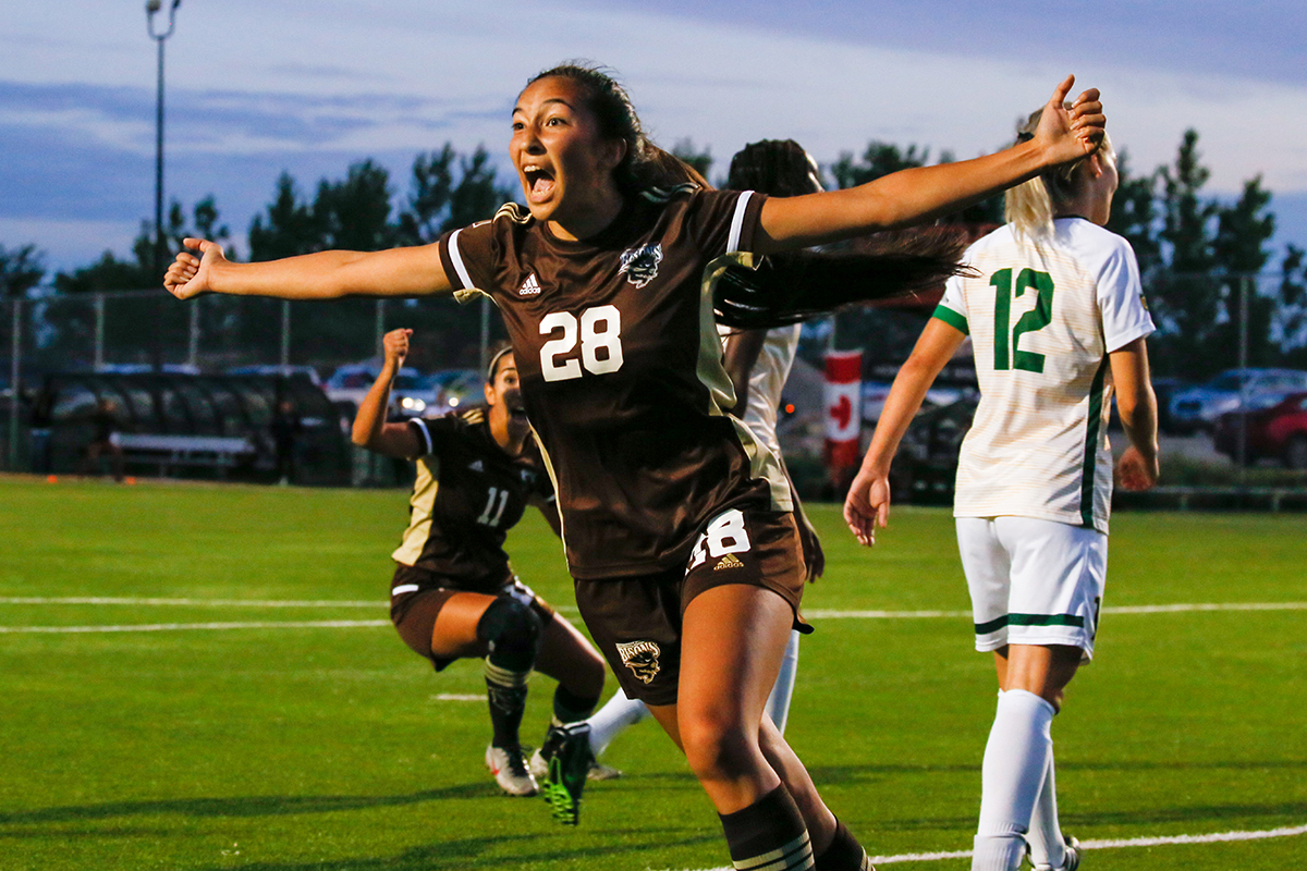 Bison women's soccer player celebrates with extended arms on the field