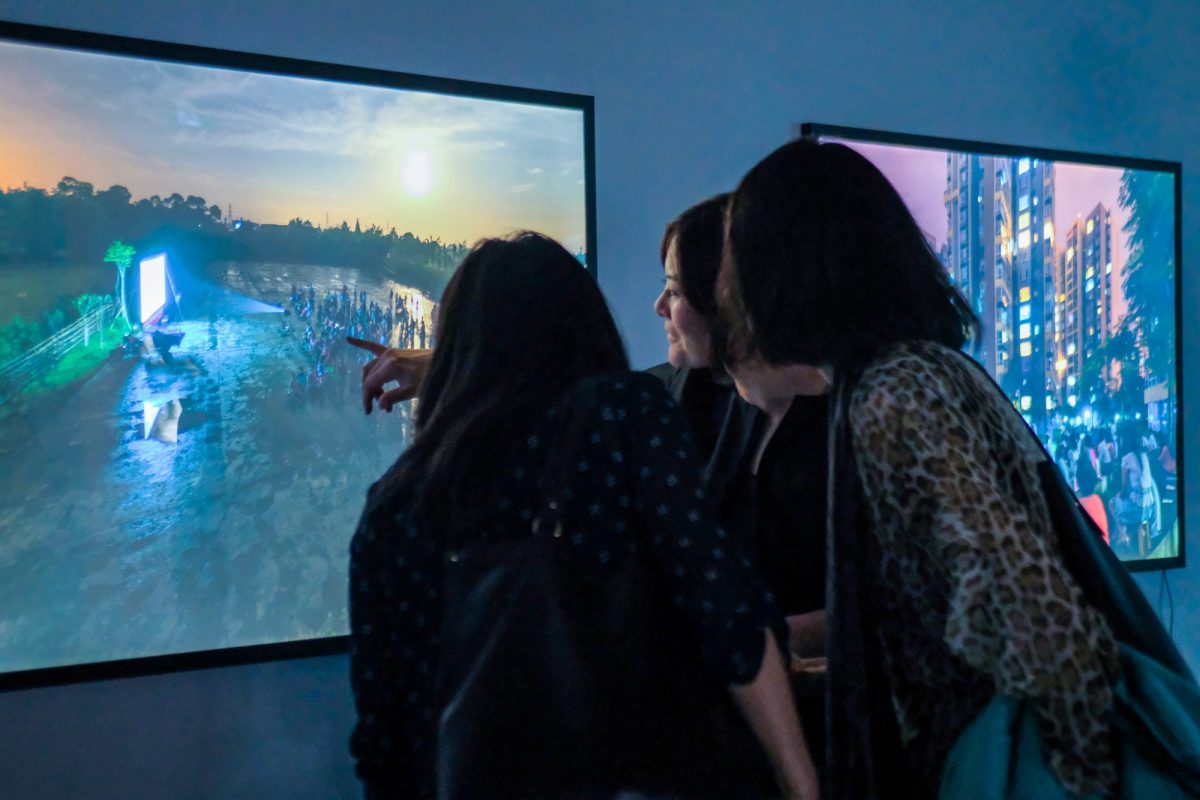 Tina Chen and a group of women studying a photo as part of a gallery exhibit.