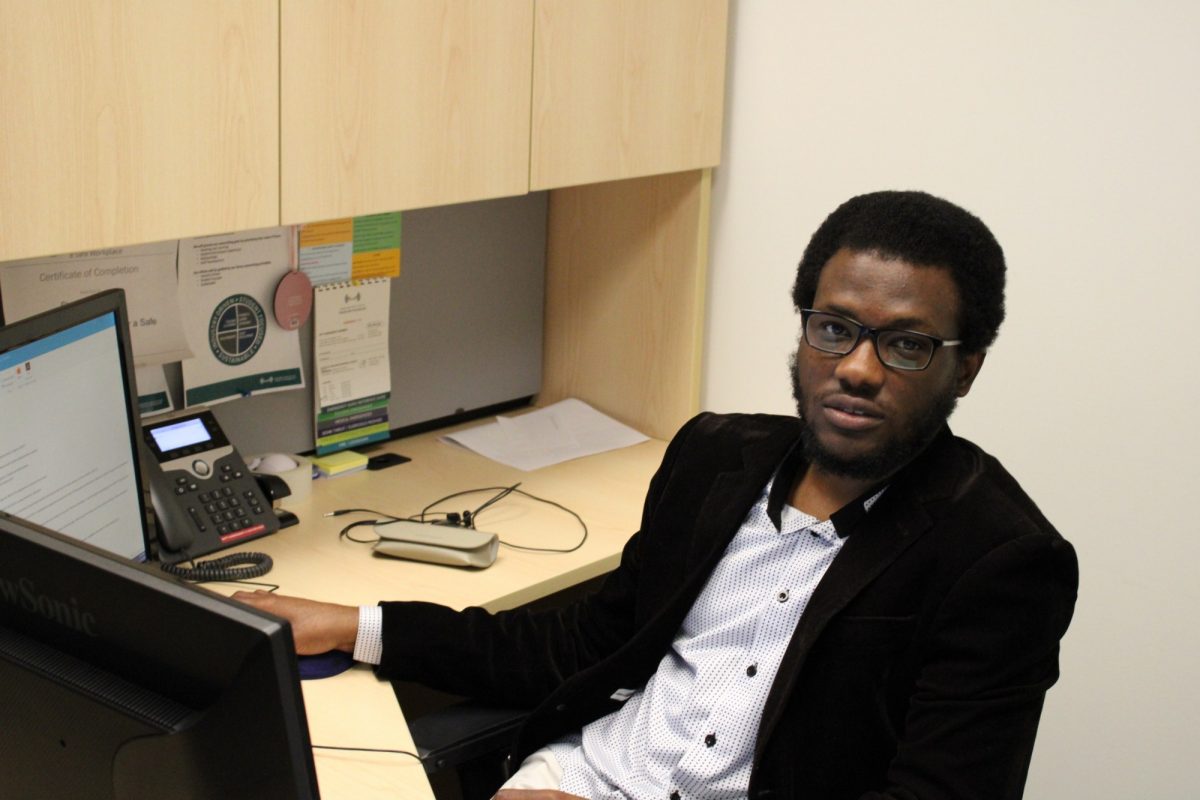 Stephen Alalade sitting at a computer desk.