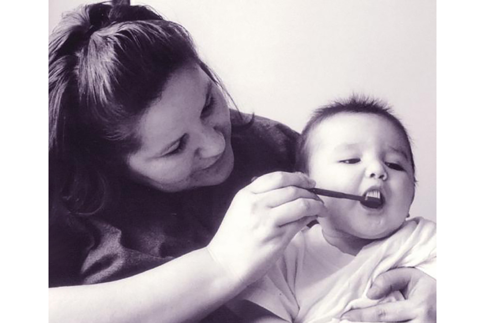 An Indigenous woman brushes her baby's teeth.