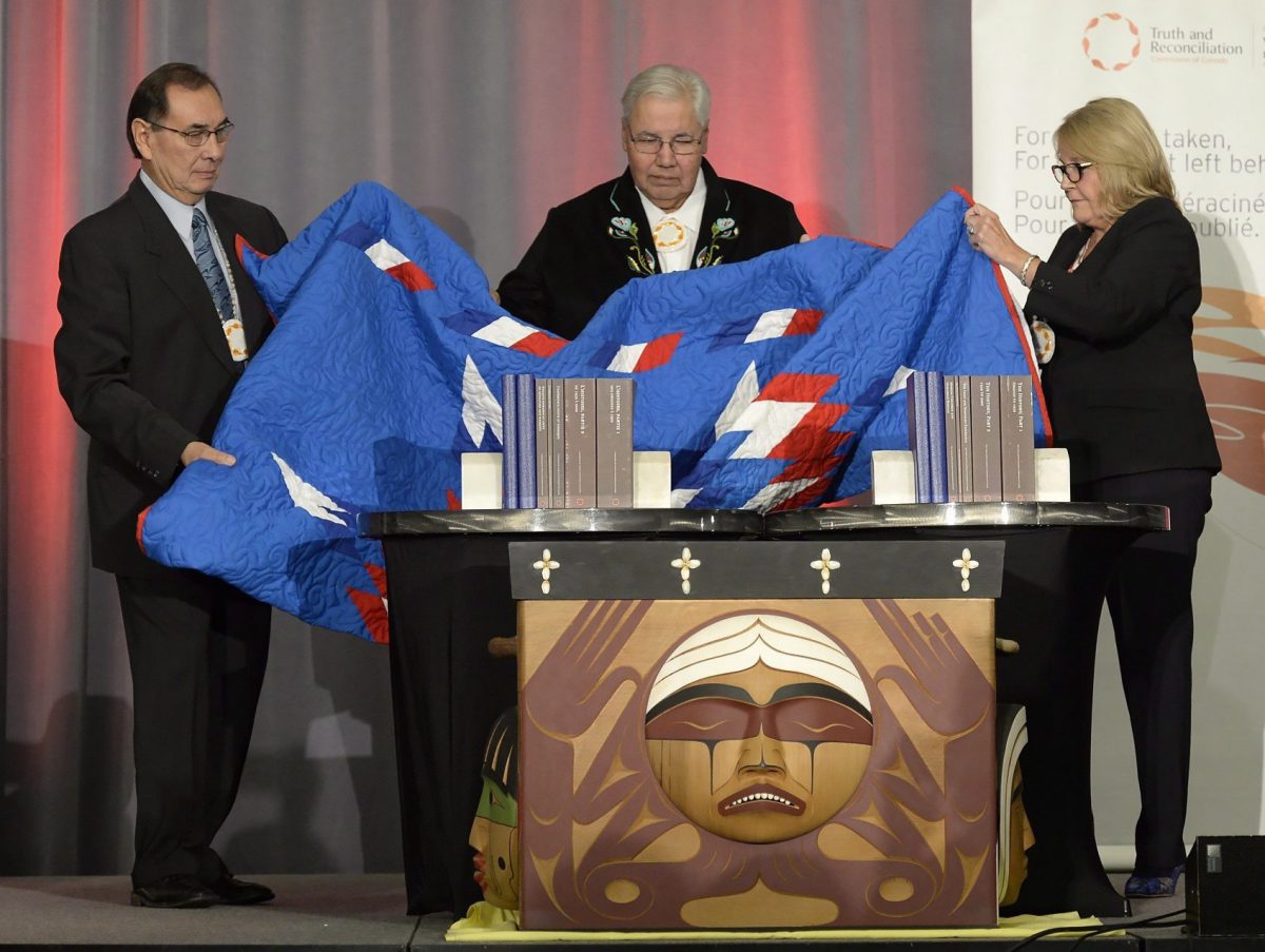 Justice Murray Sinclair (centre) and Commissioners Chief Wilton Littlechild (left) and Marie Wilson pull back a blanket to unveil the Final Report of the Truth and Reconciliation Commission of Canada on the history of Canada's residential school system, in Ottawa on Tuesday, Dec. 15, 2015. THE CANADIAN PRESS/Adrian Wyld