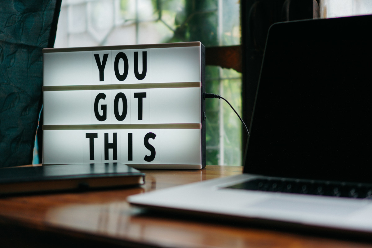 Illuminated sign on computer desk says you got this.