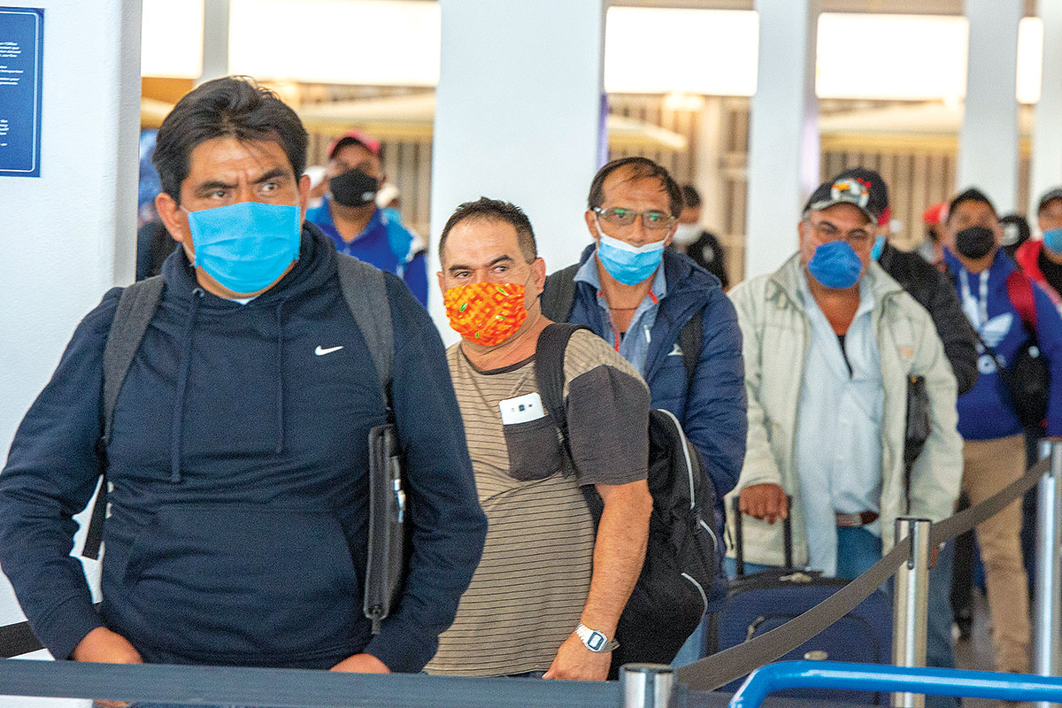 Masked migrant workers from Mexico waiting to be transported to Quebec farms after arriving at Trudeau Airport Tuesday April 14, 2020 in Montreal. // The Canadian Press/Ryan Remiorz