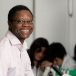 Dr. Francis Amara in a lab with young students in the background.