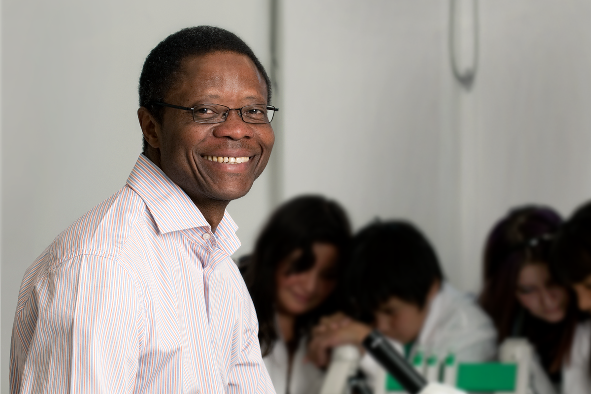 Dr. Francis Amara in a lab with young students in the background.