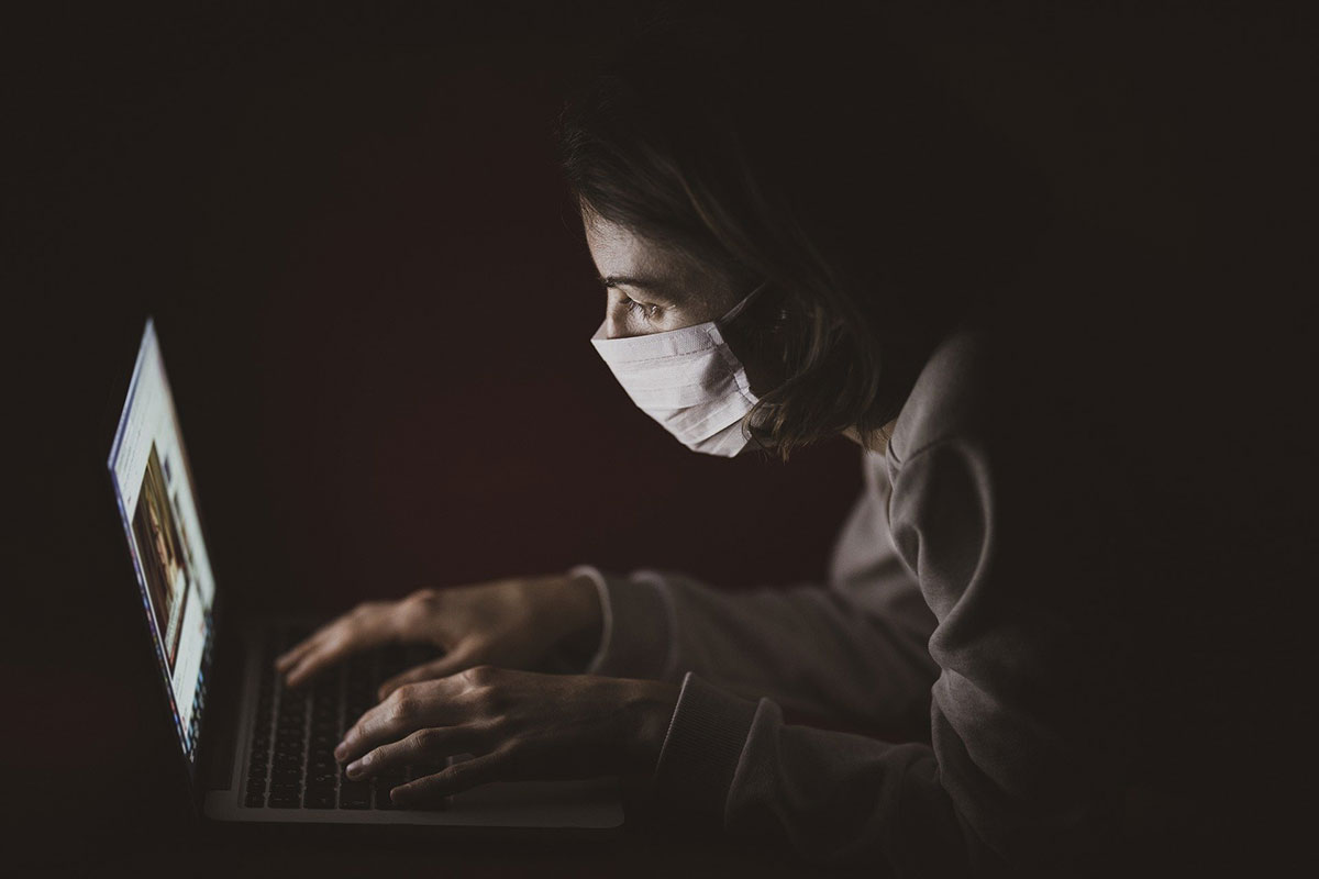 Woman wearing mask uses laptop for medical appointment. // Image from Pixabay