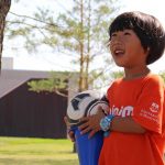 child pictured holding a soccer ball outdoors