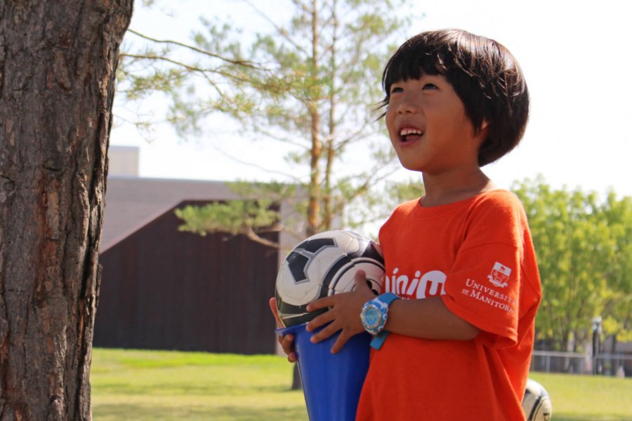 child pictured holding a soccer ball outdoors