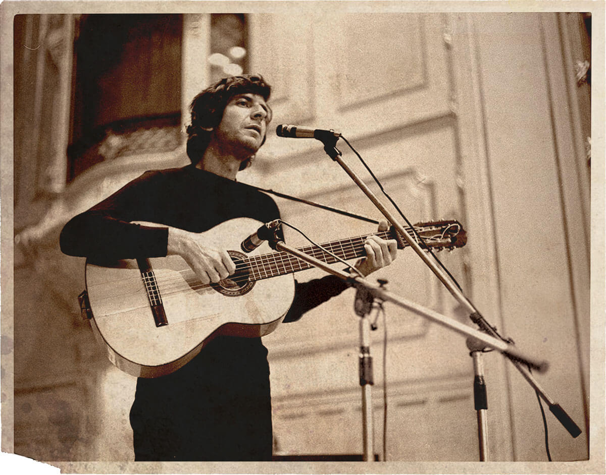 A man plays a guitar in a yellowed, vintage photo.