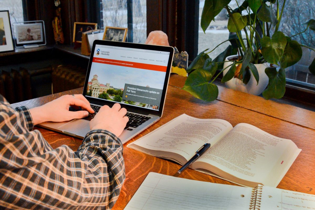 A person with a plaid shirt views the UM website on a laptop