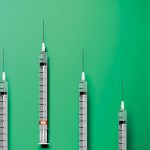 A line-up of four syringes on a green background.