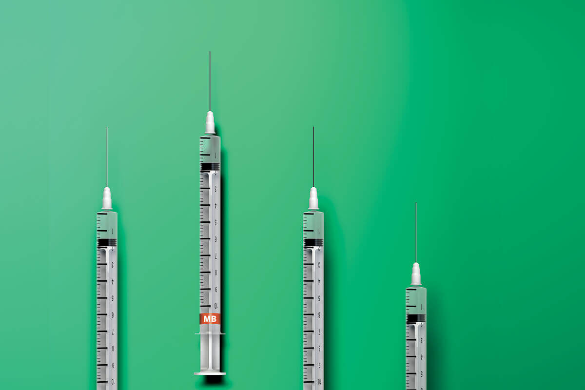 A line-up of four syringes on a green background.