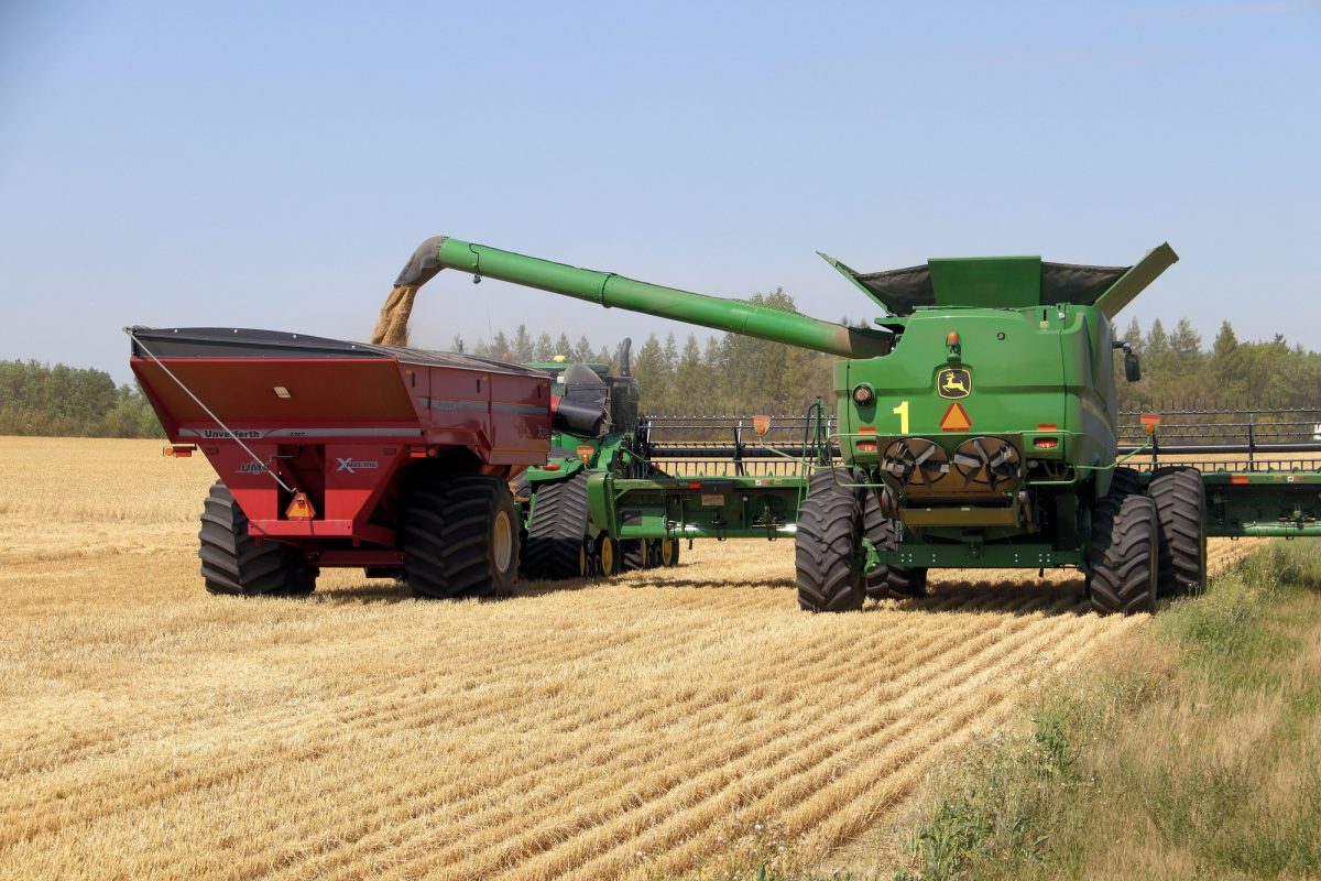 Combine and hopper truck harvesting a Prairie wheat field