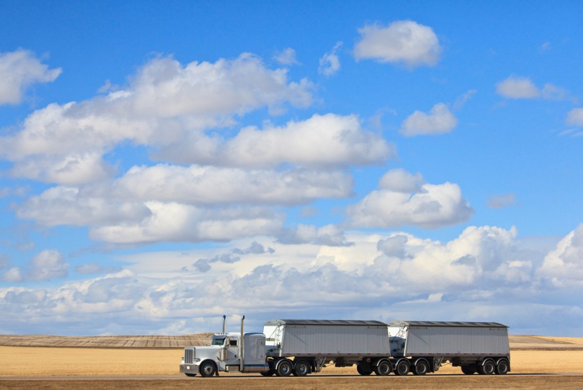 A semi truck drives across the prairie