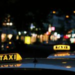 Photo shows yellow taxi lights on roofs of taxis vehicles at night. // Image from Lexi Anderson/Unsplash