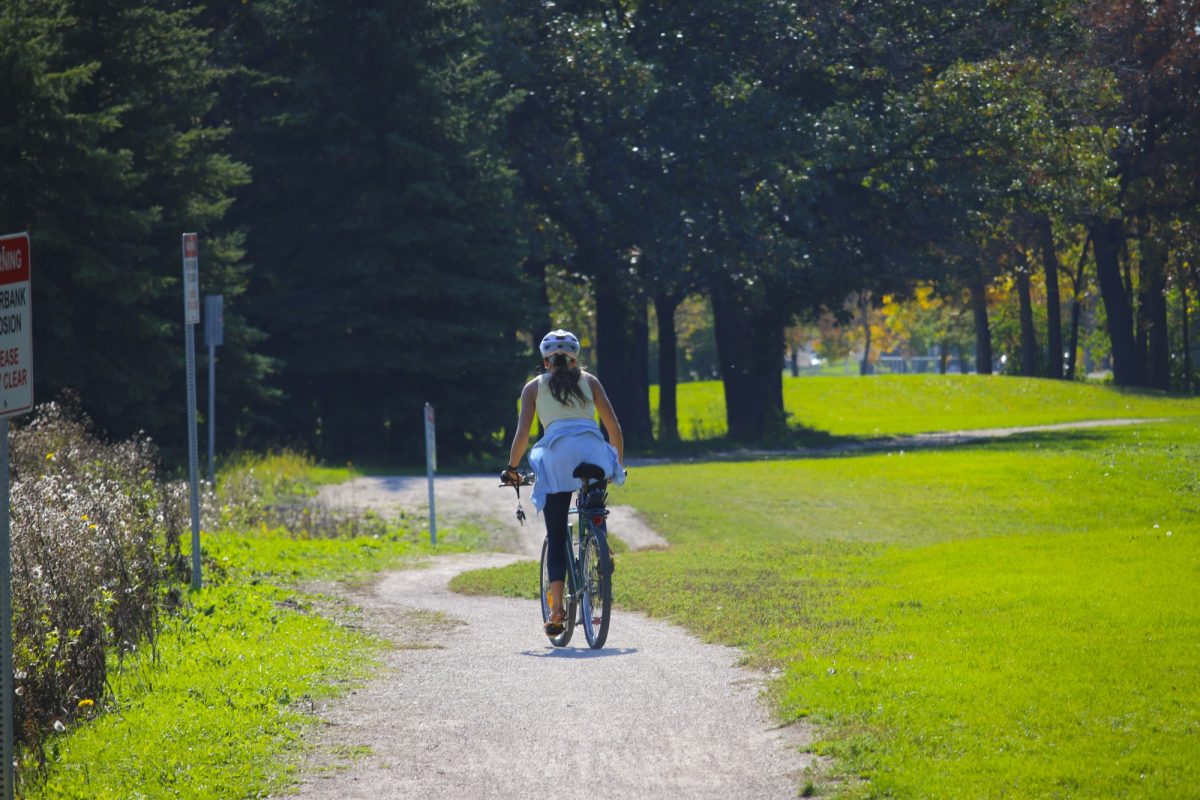 Person cycles towards Fort Garry campus on a pathway through Southwood lands.