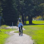 Person cycles towards Fort Garry campus on a pathway through Southwood lands.