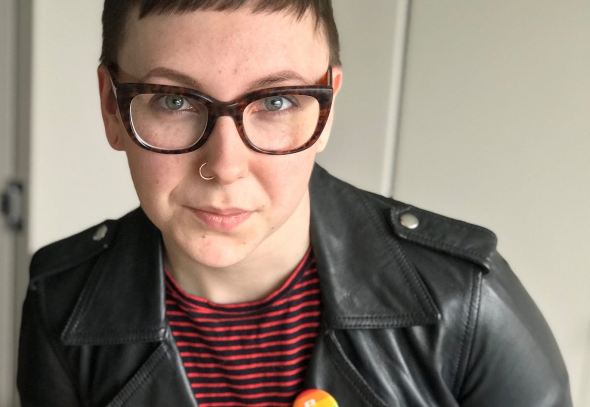 clodeup of woman wearing glasses, black leather jacket and pride pin