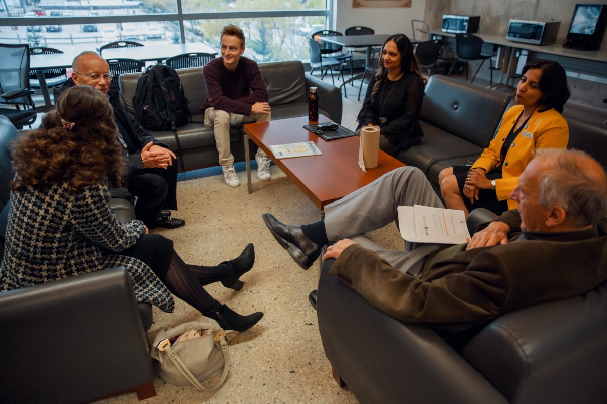 Three recipients of the College of Pharmacy Class of 1966 Scholarship sit around a coffee table with two alumni and the dean of the College of Pharmacy.