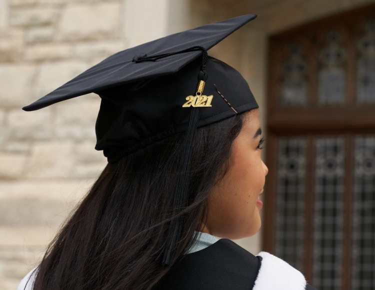 A student wears a graduation cap and on the tassel is 2021.