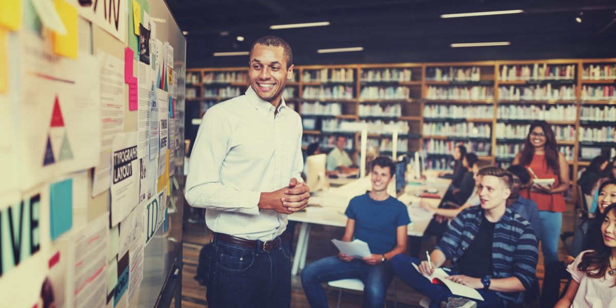 Man shares information on a bulletin board with students