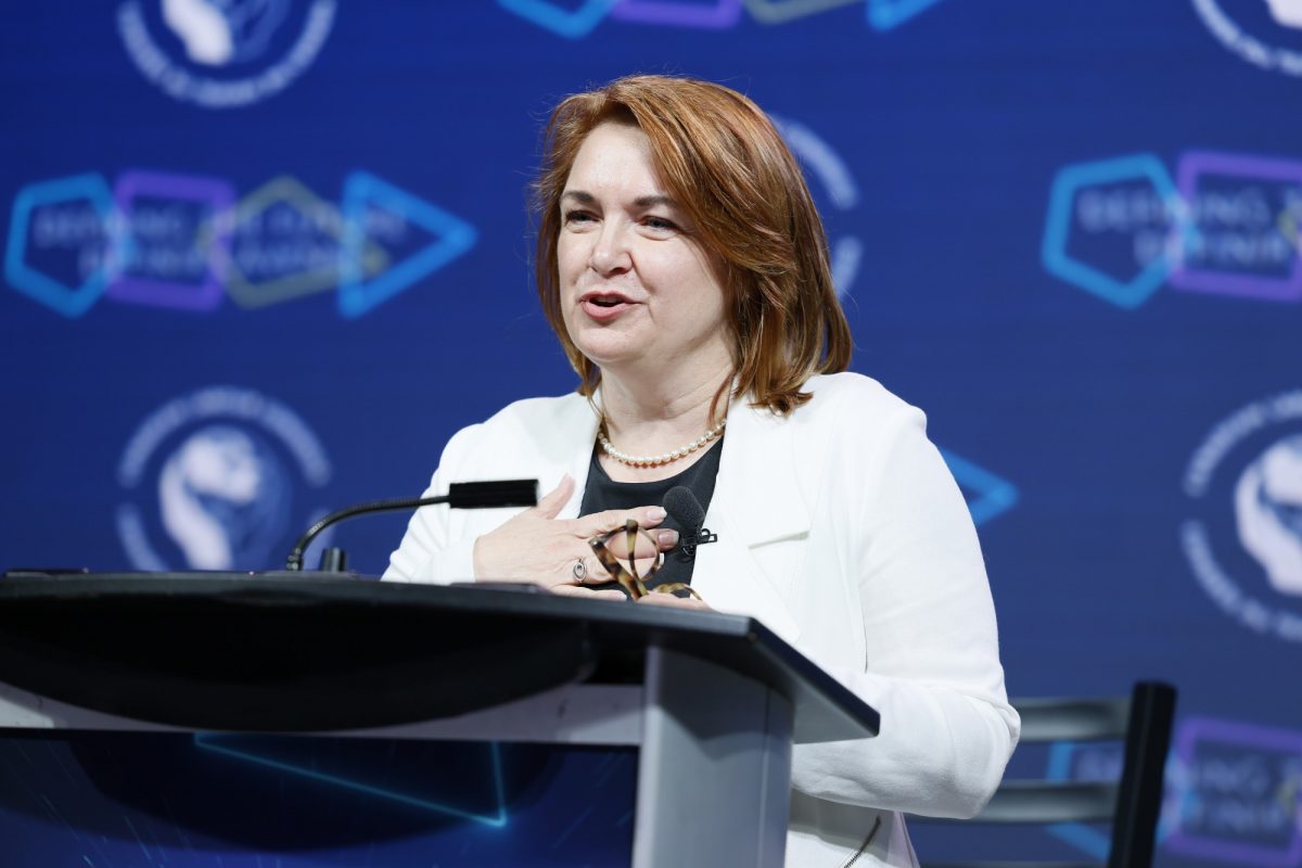 Woman speaking at podium with hand placed over her heart.